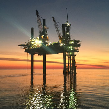 An oil rig standing high above the tide at sunset