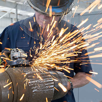 A Superior Energy Services employee cutting a pipe with sparks flying